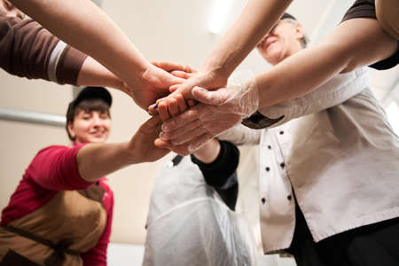 Coolinary team making pile of hands while standing at the workplace