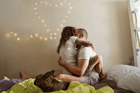 Tattooed woman embracing her man on the bedの写真素材