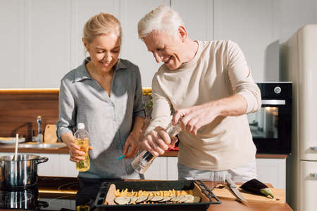 Couple of grandparents making baked vegetables togetherの写真素材