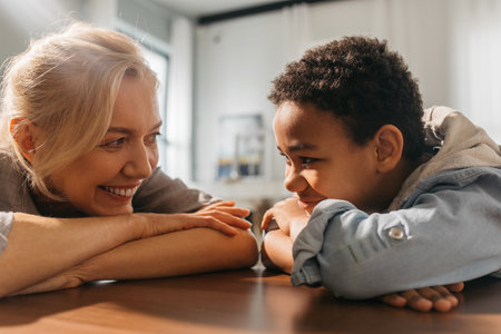 Woman smiling to her multiracial son with tenderness while sitting with him