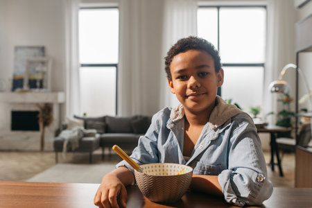 Boy smiling to the camera while sitting near the empty plateの写真素材