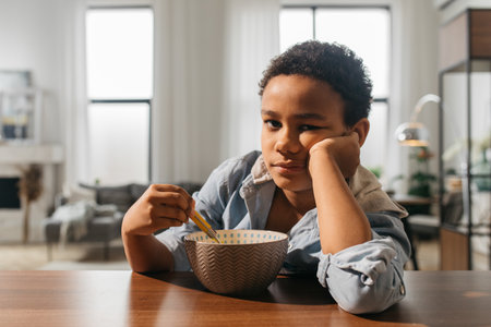 Boy looking to the camera while sitting near the empty plateの写真素材