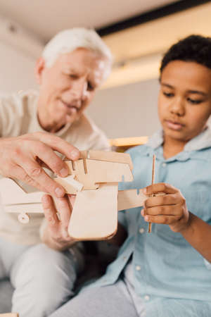 Man and his son considering wooden model of the airplane while playing