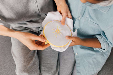 Boy looking at the embroidery while his grandmother sitting at the sofaの写真素材