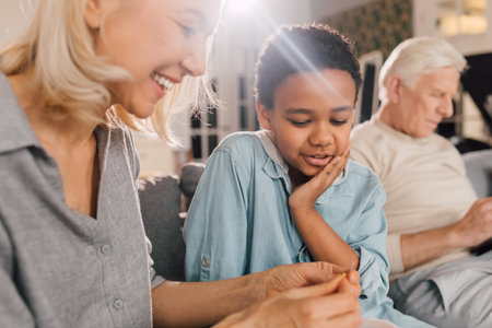 Senior woman showing a needle to her grandson while doing needlework at homeの写真素材