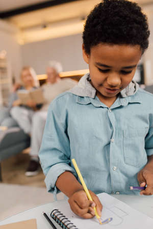 Pupil writing at notebook while distance learning online at remote virtual classの写真素材