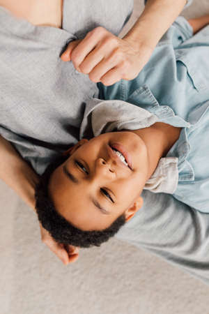 Boy resting at the knees of his caucasian mother while staying at homeの写真素材