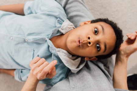 Boy laying at the knees of his granny and showing his emotionsの写真素材