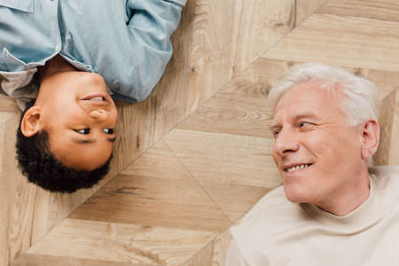 Schoolboy and his father laying at the carpet at the same poseの写真素材