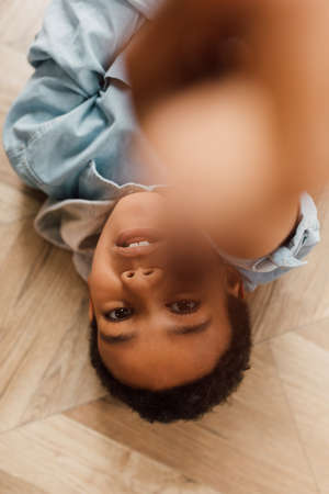 Kid laying at the floor and pointing with his finger to the cameraの写真素材