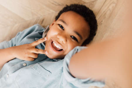 Boy laying at the floor and smiling to the camera while relaxingの写真素材