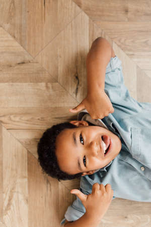 Boy laying at the floor and showing cool gesture to the cameraの写真素材