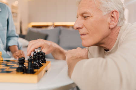 Man thinking about chess move while playing at the game with his familyの写真素材