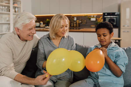 Parents sitting with their multiracial son and preparing to blowing balloonsの写真素材