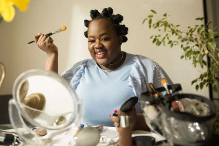 Woman preparing makeup and smiling at camera while shooting the video tutorialの写真素材