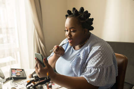 Woman blogger is showing how to make up and use cosmetics in front of the camera