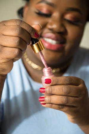 Blogger with perfect skin holding nail polish and picks up it with a brushの写真素材