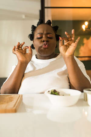 Woman trying her dish and sitting at the table around the vegetables while cookingの写真素材