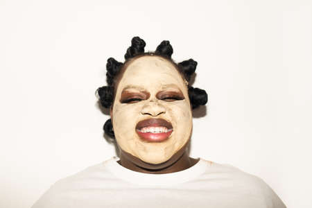 Woman with mask at her face standing with closed eyes and laughing out loud