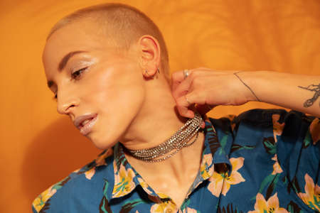 Woman wearing hawaiian shirt holding with her hand her necklace and looking awayの写真素材