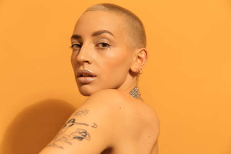 Woman with tattoos looking of her shoulder while posing at the studioの写真素材