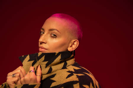 Female with nude makeup wearing stylish jacket posing at studio with red wallの写真素材