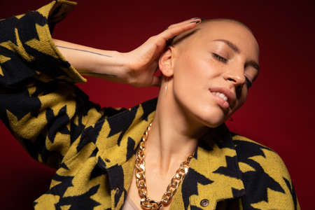 Woman with nude makeup at her face and short hair posing over red backgroundの写真素材