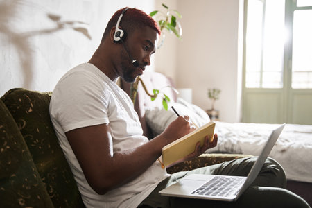 Man making notes while having zoom video conferencing call with his boss