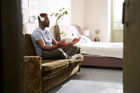Man holding hand at the mudras gesture while sitting in yoga posture and meditatingの写真素材
