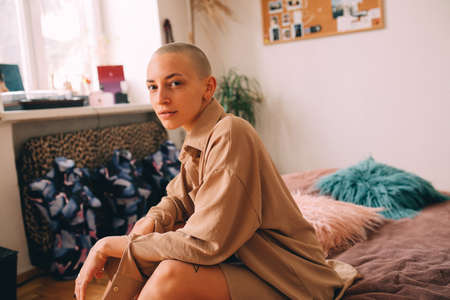 Girl with short haircut sitting at the bed and looking at the cameraの写真素材