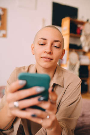 Girl with short haircut sitting at the mattress and using her smartphoneの写真素材