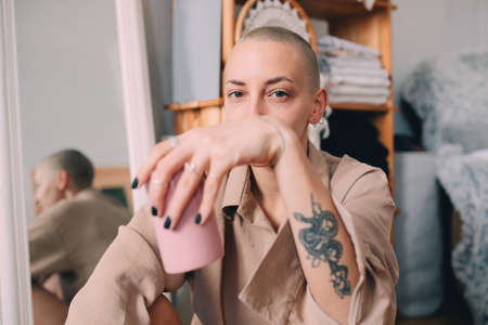Woman with short hair sitting at the floor and holding cup with beverageの写真素材