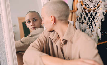 Woman sitting at the floor and looking to the mirror at her reflectionの写真素材