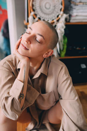 Woman with short hair and tattoos sitting at the floor with closed eyesの写真素材