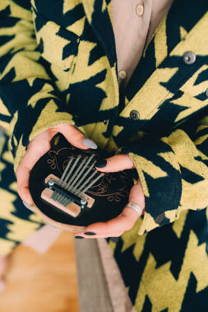 Woman holding kalimba and standing at her cozy flat at homeの写真素材