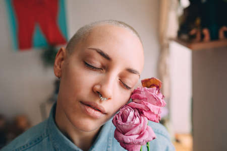 Woman with septum at her nose holding dry roses and enjoying of the moment