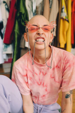 Woman wearing modern sunglasses keeping the chain in her teeth while posing