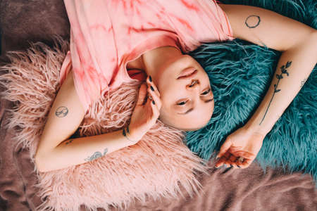 Woman wearing domestic shirt laying at the bed at homeの写真素材