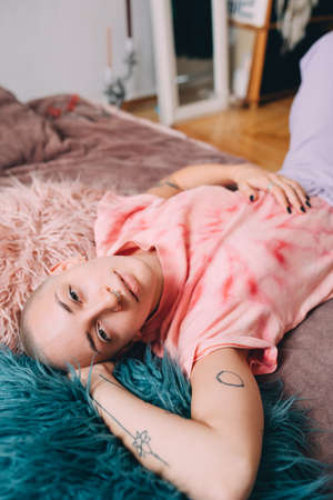 Woman with septum at her nose laying at the bed at home while having lazy mood