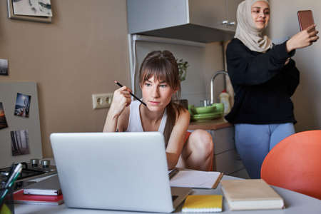 Woman holding pencil and studying attentively while doing her home taskの写真素材