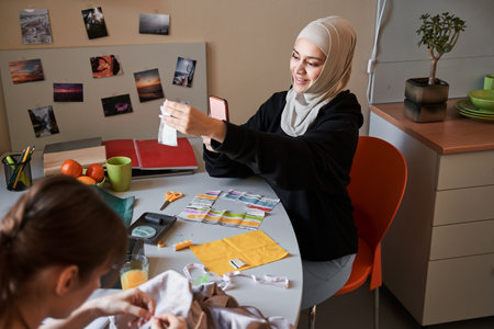 Woman wearing hijab shooting at her smartphone her handicraft from the fabricの写真素材