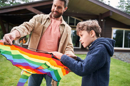 Cheerful father and son playing with kite outdoorsの写真素材