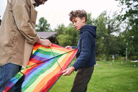 Father and son preparing kite for flying outdoorsの写真素材