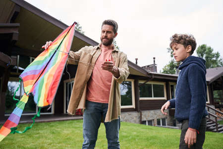 Father and son preparing colorful kite for flying outdoorsの写真素材