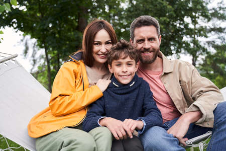 Happy family sitting on hammock swing outdoorsの写真素材