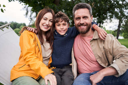 Happy parents and their son sitting on hammock swing outdoorsの写真素材