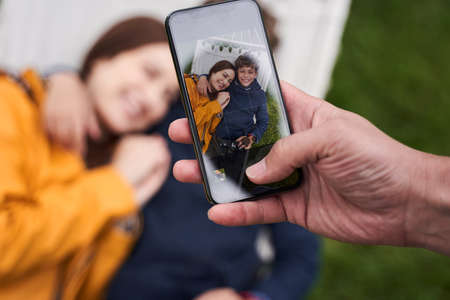 Young man photographing wife and son with smartphoneの写真素材