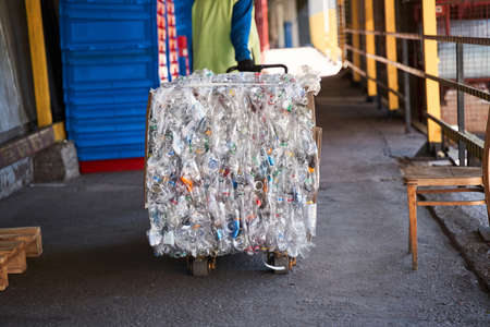 Worker carries a cart with plastic bottles