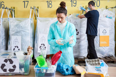 Woman in turquoise robe sorting plastic bottlesの写真素材