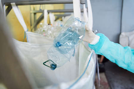 Worker holding transparent crumpled plastic bottleの写真素材